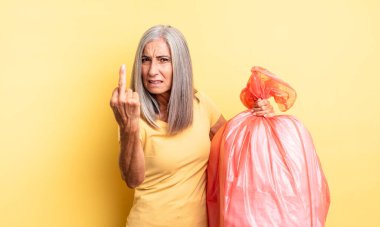 Orta yaşlı, güzel bir kadın sinirli, sinirli, asi ve agresif hissediyor. Plastik çöp torbası.
