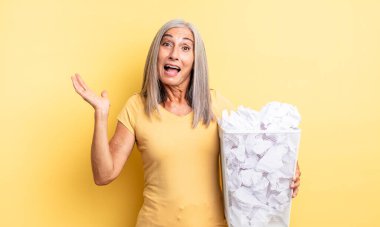 Orta yaşlı, güzel bir kadın inanılmaz bir şey karşısında mutlu ve şaşkın hissediyor. kağıt toplar başarısızlık konsepti