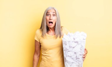 Orta yaşlı güzel bir kadın çok şaşırmış ya da şaşkın görünüyor. kağıt toplar başarısızlık konsepti