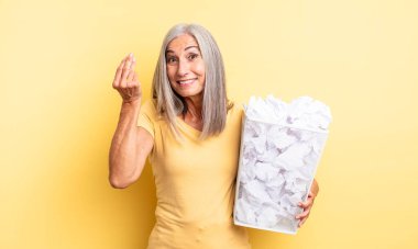 Orta yaşlı, güzel bir kadın kapiş ya da para hareketi yapıp sana ödemeni söylüyor. kağıt toplar başarısızlık konsepti