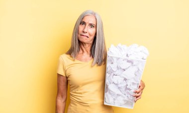 Orta yaşlı güzel bir kadın kafası karışmış ve şaşkın görünüyor. kağıt toplar başarısızlık konsepti