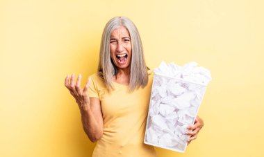 Orta yaşlı, güzel bir kadın umutsuz, sinirli ve stresli görünüyor. kağıt toplar başarısızlık konsepti