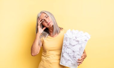 Orta yaşlı, güzel bir kadın bıkkın, yorgun ve uykulu hissediyor. kağıt toplar başarısızlık konsepti