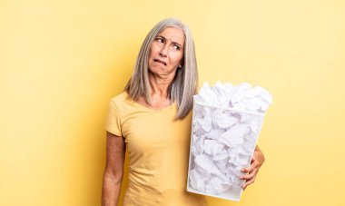 Orta yaşlı, güzel bir kadın şaşkın ve kafası karışık hissediyor. kağıt toplar başarısızlık konsepti