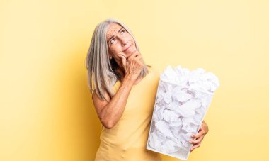 Orta yaşlı, düşünceli, kuşkulu ve kafası karışık bir kadın. kağıt toplar başarısızlık konsepti