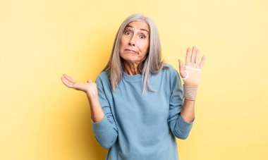 Orta yaşlı, güzel bir kadın şaşkın, şaşkın ve şüpheci hissediyor. el bandajı konsepti