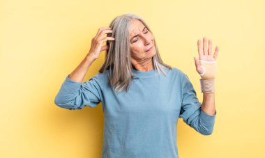 Orta yaşlı güzel bir kadın mutlu bir şekilde gülümsüyor ve hayal kuruyor ya da şüphe ediyor. el bandajı konsepti