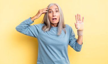 Orta yaşlı, güzel bir kadın mutlu, şaşkın ve şaşırmış görünüyor. el bandajı konsepti