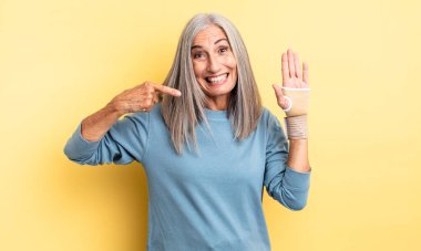 Orta yaşlı, güzel bir kadın, kendine güvenerek gülümsüyor. el bandajı konsepti