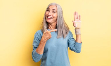 Orta yaşlı, güzel bir kadın heyecanlı ve şaşırmış görünüyor. el bandajı konsepti