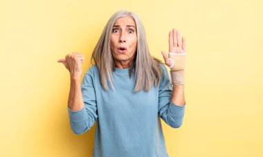 Orta yaşlı, güzel bir kadın inançsızlıktan şaşkın şaşkın bakıyor. el bandajı konsepti