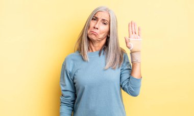 Orta yaşlı, güzel bir kadın üzgün ve mızmızlanıyor. Mutsuz bir bakışı var ve ağlıyor. el bandajı konsepti