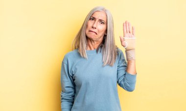 Orta yaşlı güzel bir kadın kafası karışmış ve şaşkın görünüyor. el bandajı konsepti