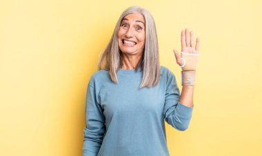 Orta yaşlı, güzel bir kadın mutlu ve hoş bir şekilde şaşırmış görünüyor. el bandajı konsepti