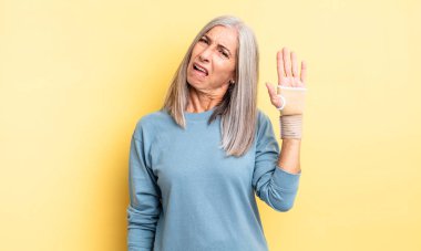 Orta yaşlı, güzel bir kadın şaşkın ve kafası karışık hissediyor. el bandajı konsepti