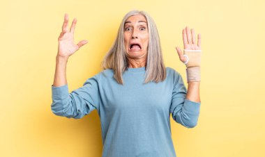 Orta yaşlı, güzel bir kadın ellerini havaya kaldırarak çığlık atıyor. el bandajı konsepti