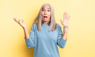 Orta yaşlı güzel bir kadın son derece şaşkın ve şaşırmış hissediyor. el bandajı konsepti