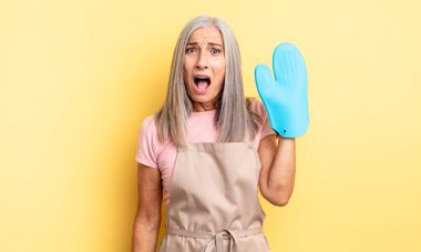 Orta yaşlı güzel bir kadın çok şaşırmış ya da şaşkın görünüyor. fırın eldiveni kavramı