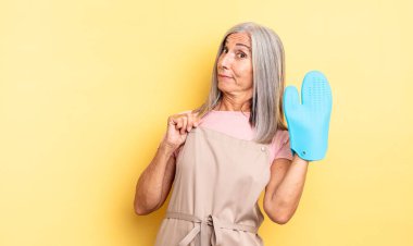 Orta yaşlı, güzel bir kadın kibirli, başarılı, pozitif ve gururlu görünüyor. fırın eldiveni kavramı