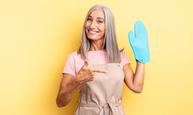 Orta yaşlı, güzel bir kadın heyecanlı ve şaşırmış görünüyor. fırın eldiveni kavramı