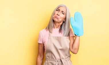 Orta yaşlı, güzel bir kadın üzgün ve mızmızlanıyor. Mutsuz bir bakışı var ve ağlıyor. fırın eldiveni kavramı