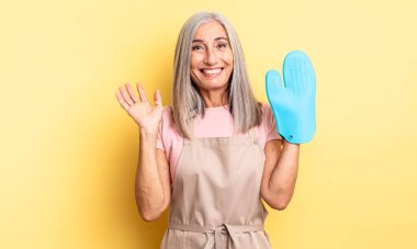 Orta yaşlı, güzel bir kadın kendini mutlu hissediyor. Bir çözüm ya da fikir bulduğuna şaşırıyor. fırın eldiveni kavramı
