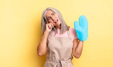 Orta yaşlı, güzel bir kadın bıkkın, yorgun ve uykulu hissediyor. fırın eldiveni kavramı