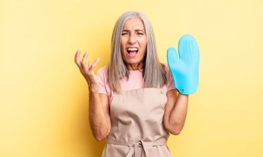 Orta yaşlı, güzel bir kadın umutsuz, sinirli ve stresli görünüyor. fırın eldiveni kavramı