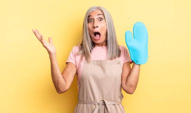 Orta yaşlı güzel bir kadın son derece şaşkın ve şaşırmış hissediyor. fırın eldiveni kavramı
