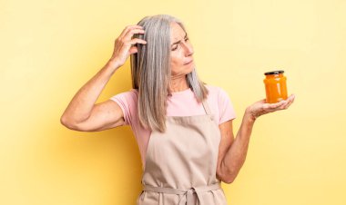 Orta yaşlı güzel bir kadın mutlu bir şekilde gülümsüyor ve hayal kuruyor ya da şüphe ediyor. Şeftali reçeli