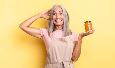 Orta yaşlı, güzel bir kadın stresli, endişeli ya da korkmuş, elleri başının üstünde. Şeftali reçeli