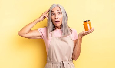 Orta yaşlı, güzel bir kadın mutlu, şaşkın ve şaşırmış görünüyor. Şeftali reçeli