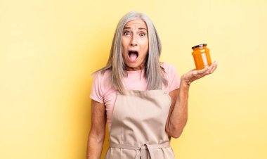 Orta yaşlı güzel bir kadın çok şaşırmış ya da şaşkın görünüyor. Şeftali reçeli