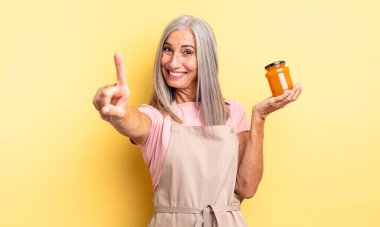 Orta yaşlı, güzel bir kadın gururla gülümsüyor ve kendinden emin bir numara oluyor. Şeftali reçeli