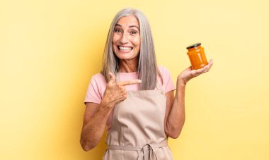 Orta yaşlı, güzel bir kadın heyecanlı ve şaşırmış görünüyor. Şeftali reçeli