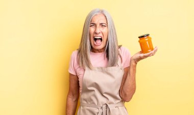 Orta yaşlı, güzel bir kadın agresif bir şekilde bağırıyor, çok kızgın görünüyor. Şeftali reçeli