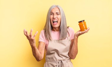 Orta yaşlı, güzel bir kadın sinirli, sinirli ve sinirli görünüyor. Şeftali reçeli