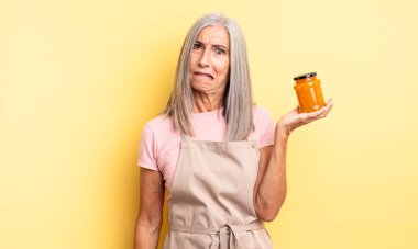 Orta yaşlı güzel bir kadın kafası karışmış ve şaşkın görünüyor. Şeftali reçeli
