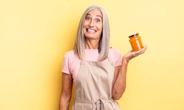 Orta yaşlı, güzel bir kadın mutlu ve hoş bir şekilde şaşırmış görünüyor. Şeftali reçeli