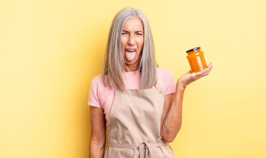 Orta yaşlı, güzel bir kadın iğreniyor, sinirleniyor ve dili dışarı çıkıyor. Şeftali reçeli