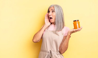 Orta yaşlı, güzel bir kadın mutlu, heyecanlı ve şaşırmış hissediyor. Şeftali reçeli