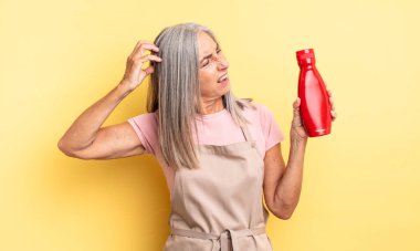 Orta yaşlı, güzel bir kadın şaşkın ve kafası karışık, kaşınıyor. Ketçap konsepti