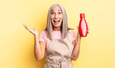 Orta yaşlı, güzel bir kadın inanılmaz bir şey karşısında mutlu ve şaşkın hissediyor. Ketçap konsepti