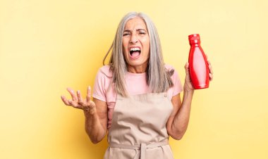 Orta yaşlı, güzel bir kadın sinirli, sinirli ve sinirli görünüyor. Ketçap konsepti
