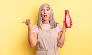 Orta yaşlı, güzel bir kadın inançsızlıktan şaşkın şaşkın bakıyor. Ketçap konsepti