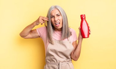 Orta yaşlı, güzel bir kadın mutsuz ve stresli görünüyor, intihar jesti silah işareti yapıyor. Ketçap konsepti