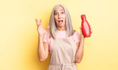 Orta yaşlı, güzel bir kadın ellerini havaya kaldırarak çığlık atıyor. Ketçap konsepti