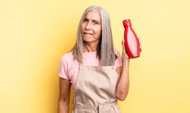 Orta yaşlı güzel bir kadın kafası karışmış ve şaşkın görünüyor. Ketçap konsepti