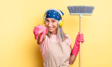 Orta yaşlı, güzel bir kadın kamerayı işaret ederek seni seçiyor. ev ve süpürge kavramı