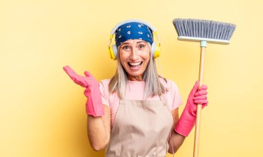 Orta yaşlı, güzel bir kadın inanılmaz bir şey karşısında mutlu ve şaşkın hissediyor. ev ve süpürge kavramı